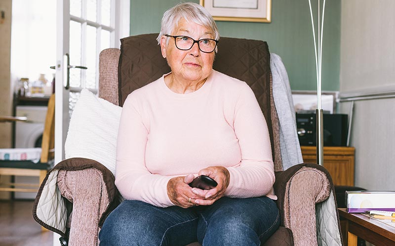 Femme âgée assise dans un fauteuil releveur à son domicile.