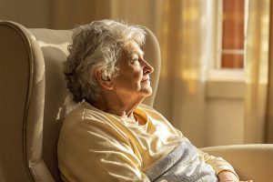 Femme âgée assise dans un fauteuil près d'une fenêtre
